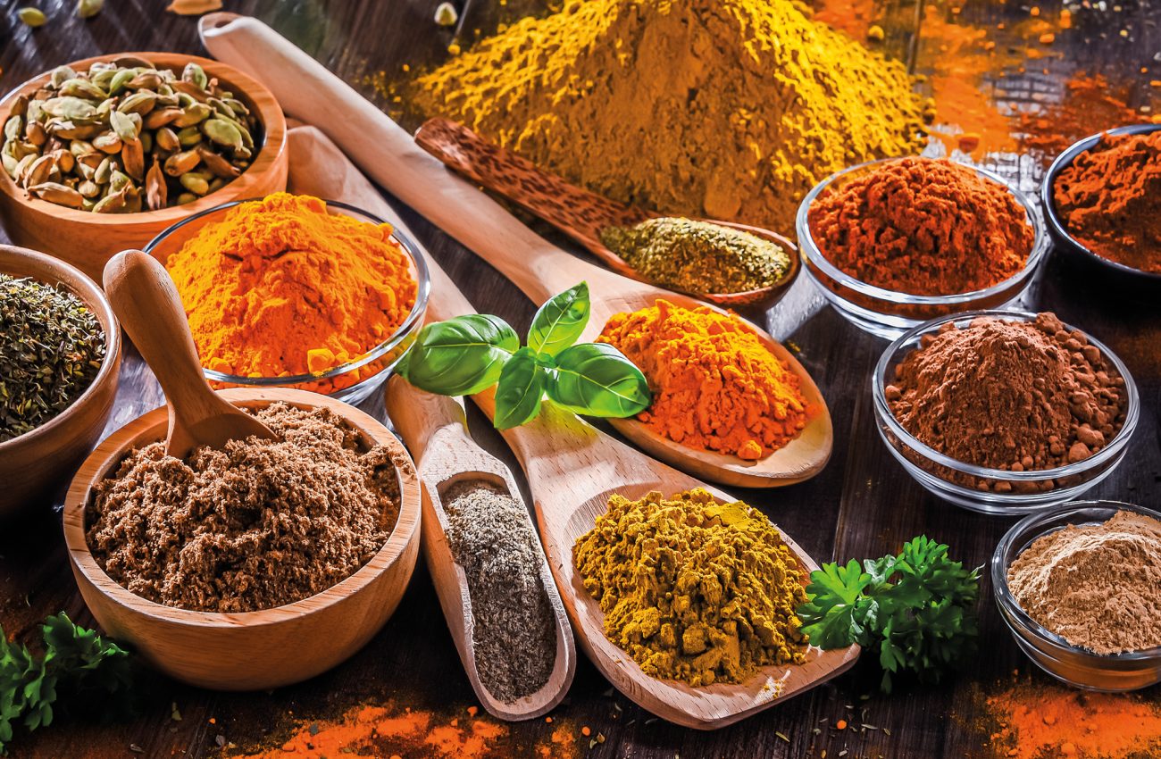 Variety of spices on wooden kitchen table.