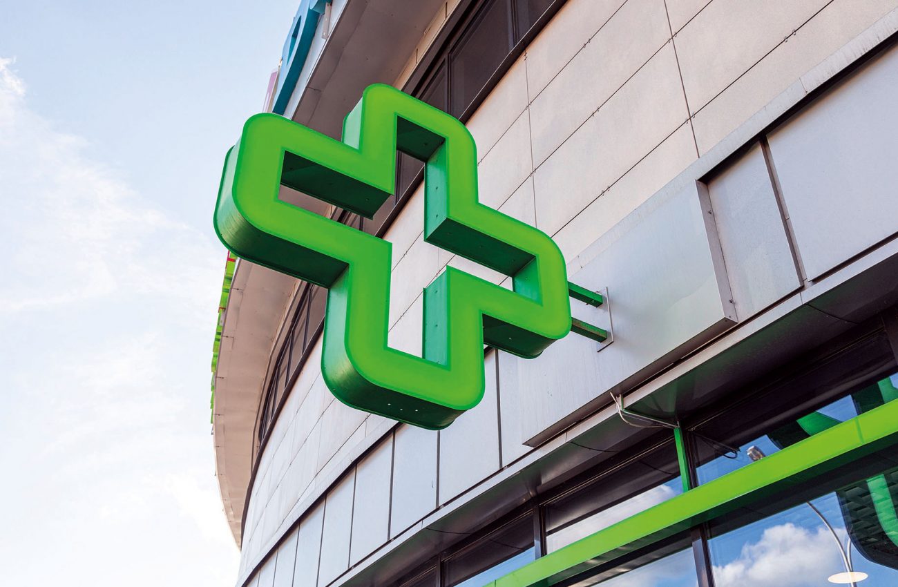 Close up of green cross   sign of pharmacy on glass building