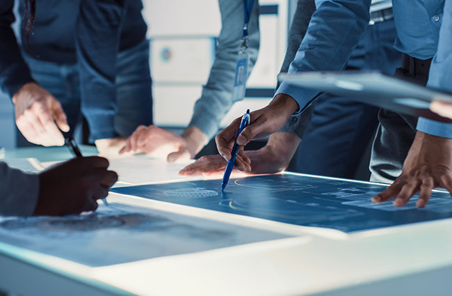 Engineer, Scientists and Developers Gathered Around Illuminated Engineer, Scientists and Developers Gathered Around Illuminated Conference Table in Technology Research Center, Talking, Finding Solution and Analysing Industrial Engine Design. Close-up Hands Shot